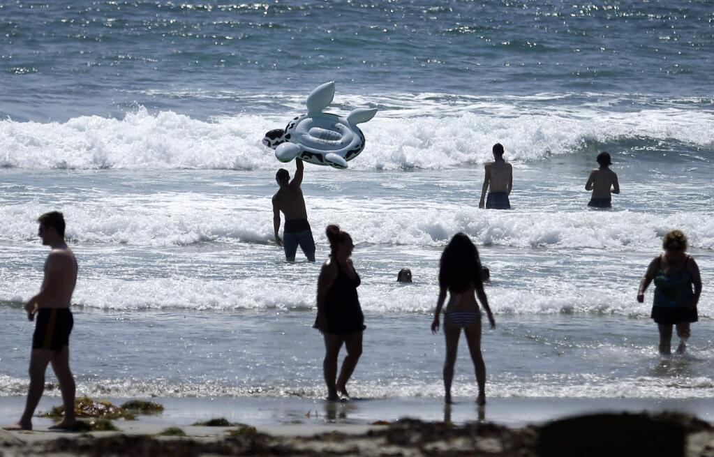 This, June 24, 2014, file photo shows people swimming on a sunny day at Mission Beach in San Diego. Stop sunbathing and using indoor tanning beds, the acting U.S. surgeon general warned in a report that cites an alarming 200 percent jump in deadly melanoma cases since 1973. (AP Photo/Gregory Bull, File)