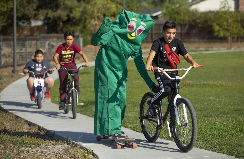 Jesus Hernandez pulls a skateboarding Gumby around the Bayer Farm park in Roseland on Thursday. LandPaths hosted a pop-up Halloween adventure day with pumpkin carving, a costume parade and pumpkin tacos. (photo by John Burgess/The Press Democrat)