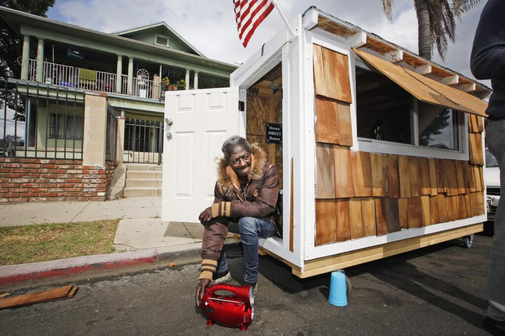 Irene 'Smokie' McGhee, a woman who had been sleeping on the streets in a South Los Angeles neighborhood, listens to music on the doorway of her newly built tiny home Thursday, May 7, 2015, in Los Angeles. It is unclear if the city would enforce rules for these homes. Smokie said police have told her she wont be bothered as long as she moves the home , small enough to fit in a parking space, every three days. And the structure is so small that it wouldnt require permits if built on private property, said Luke Zamperini, spokesman for the Building and Safety department. (AP Photo/Damian Dovarganes)