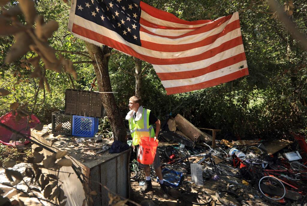 A worker from Catholic Charities looks for salvageable tools, Monday August 14, 2017 at Homeless Hill at the Farmers Lane extension in Santa Rosa, after city personnel relocated the residents of the homeless encampments. Hazardous waste, feces, food, household furnishings, bikes and thousands of pounds of clothes and other debris are being removed from the site. (Kent Porter / The Press Democrat) 2017