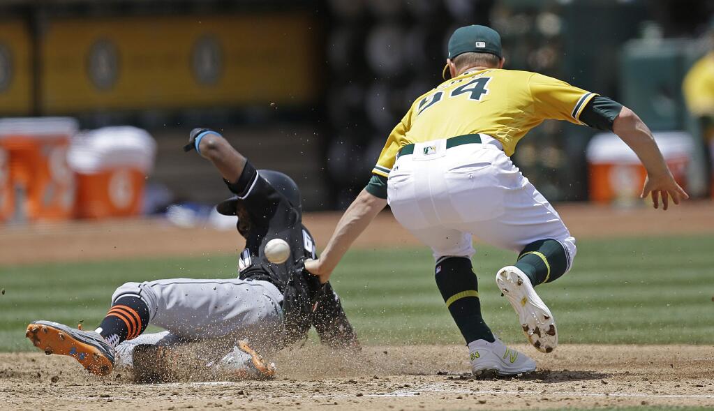 Miami Marlins' Dee Gordon, left, scores past Oakland Athletics pitcher Sonny Gray in the fourth inning of a baseball game Wednesday, May 24, 2017, in Oakland, Calif. Gordon scored on a wild pitch by Gray. (AP Photo/Ben Margot)