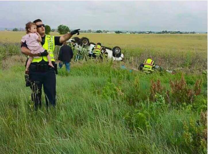 Officer Nick Struck of Colorado is seen here holding a little girl. They are both looking off into the distance while he sings her “Twinkle, Twinkle Little Star.” Her attention is on whatever Officer Struck is showing her. But behind them, rescuers are extracting the body of her father who just died in a car crash. Officer Struck told 9NEWS, “When you hear that there's children involved, I'll tell you what, everyone that responds to that scene, you get that pit in your stomach. The first thing we do when we get on scene is we just try to, if we can comfort anybody, of course we're going to go to the kids.” (Jessica Matrious / Brighton Police Dept.)