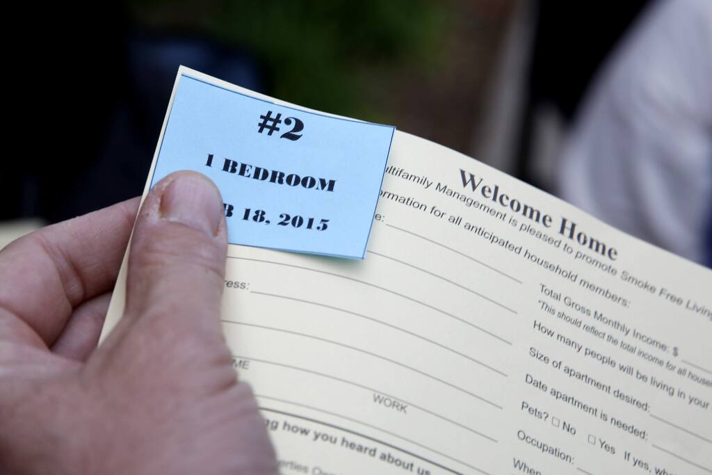 Danny Hall, property manager of USA Multifamily Management Inc., hands out numbers to people as they wait in line to apply for the new Tierra Springs Apartments, for moderate and middle income households, at Terracina at Santa Rosa apartment complex in Santa Rosa, California on Wednesday, February 18, 2015. (BETH SCHLANKER/ The Press Democrat)