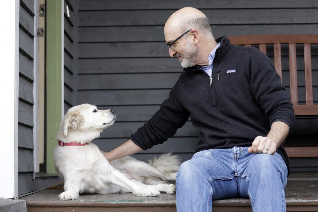 In this Monday, Nov. 11, 2019 photo, University of Washington School of Medicine researcher Daniel Promislow, the principal investigator of the Dog Aging Project grant, sits with his elderly dog Frisbee at their home in Seattle. Can old dogs teach us new tricks? Hoping to shed light on human longevity, scientists need 10,000 pet dogs for the largest-ever study of healthy aging in canines. (AP Photo/Elaine Thompson)