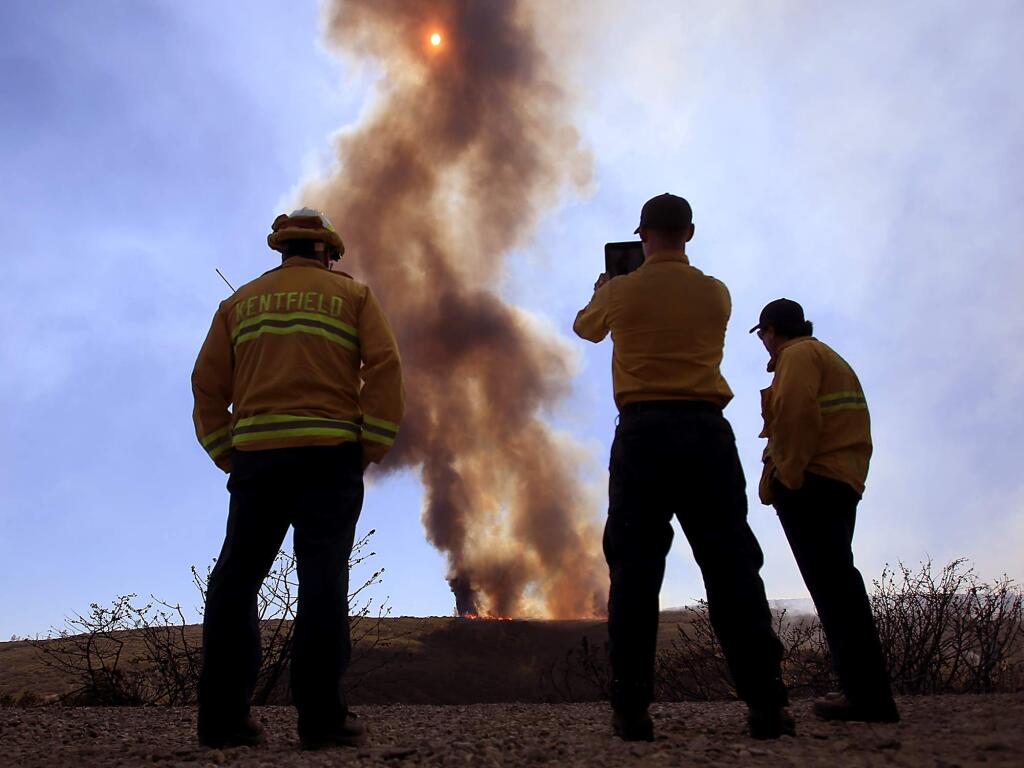 From left, Michael Hadfield of Kentfield, Jeff Shelton of Orange County and Jude Olivas of Newport Beach watch a backfire on an unburned portion of the Jerusalem fire, Friday Aug. 14, 2015 off Morgan Valley Road. (Kent Porter / Press Democrat) 2015