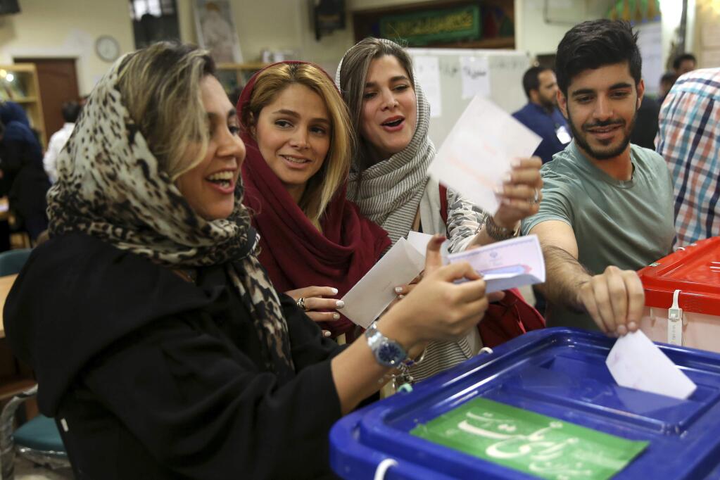Joyful voters cast their ballots for the presidential election at a polling station in Tehran, Iran, Friday, May 19, 2017. Millions of Iranians voted late into the night Friday to decide whether incumbent President Hassan Rouhani deserves another four years in office after securing a landmark nuclear deal, or if the sluggish economy demands a new hard-line leader who could return the country to a more confrontational path with the West. (AP Photo/Vahid Salemi)