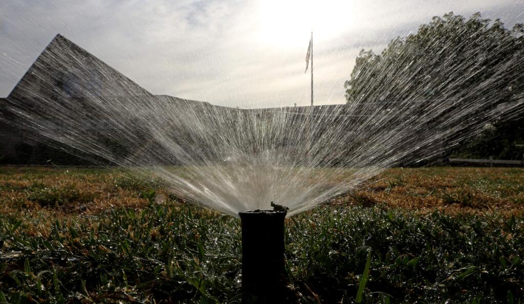 FILE - In this July 15, 2014, file photo sprinklers water a lawn in Sacramento, Calif. California residents have to turn off their sprinklers, and restaurants won't give customers water unless they ask under new drought regulations approved Tuesday, March 17, 2015. (AP Photo/Rich Pedroncelli, File)