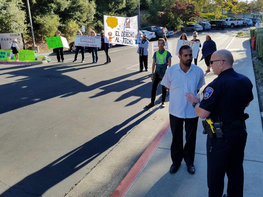 The North Bay Organizing Projects Davin Cárdenas speaks to a police officer in Santa Rosa during a protest outside the offices of the California Apartment Association to call attention to what the organization says are fraudulent efforts by petition gatherers trying to overturn the city's new rent control law on Thursday, Sept. 22, 2016. (KEVIN MCCALLUM/ PD)