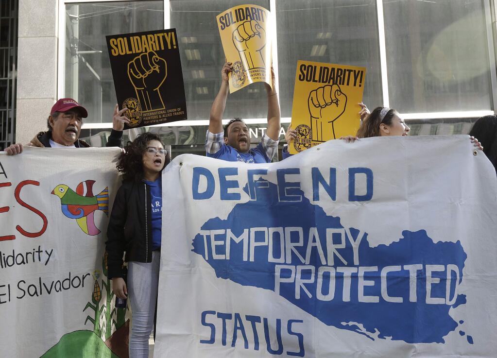 Supporters of temporary protected status immigrants hold signs and cheer at a rally before a news conference announcing a lawsuit against the Trump administration over its decision to end a program that lets immigrants live and work legally in the United States outside of a federal courthouse in San Francisco, Monday, March 12, 2018. Plaintiffs are alleging the decision to end temporary protected status for El Salvador, Haiti, Nicaragua and Sudan was racially motivated. (AP Photo/Jeff Chiu)