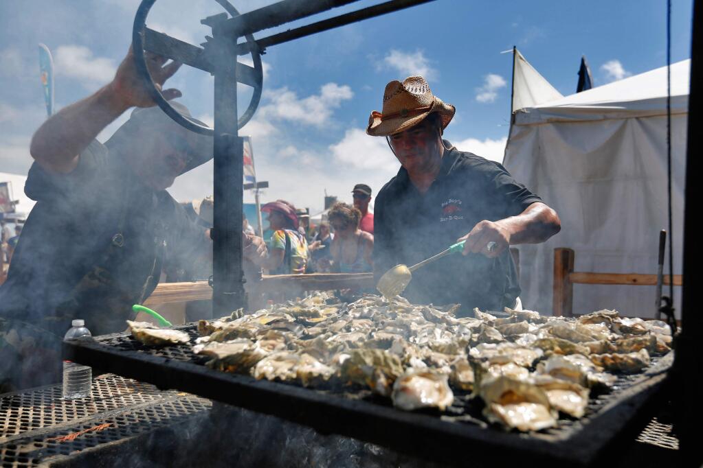 Big Boys Bar-B-Que head chef Art Flores, right, bastes oysters with garlic sauce while Brian Britton adjusts the grill during the Bodega Seafood, Art and Wine Festival in Bodega, California on Saturday, August 29, 2015. (Alvin Jornada / The Press Democrat)