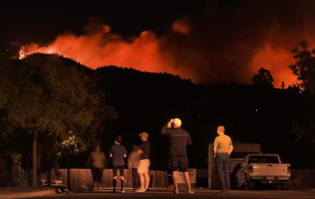 Woken in the dead of night on an order to evacuate, Skyhawk residents watch the glow of an approaching fire from their Skyhawk Homes near Los Alamos Road in Santa Rosa, Saturday Oct. 14, 2017. They eventually left the area. (Kent Porter / The Press Democrat) 2017