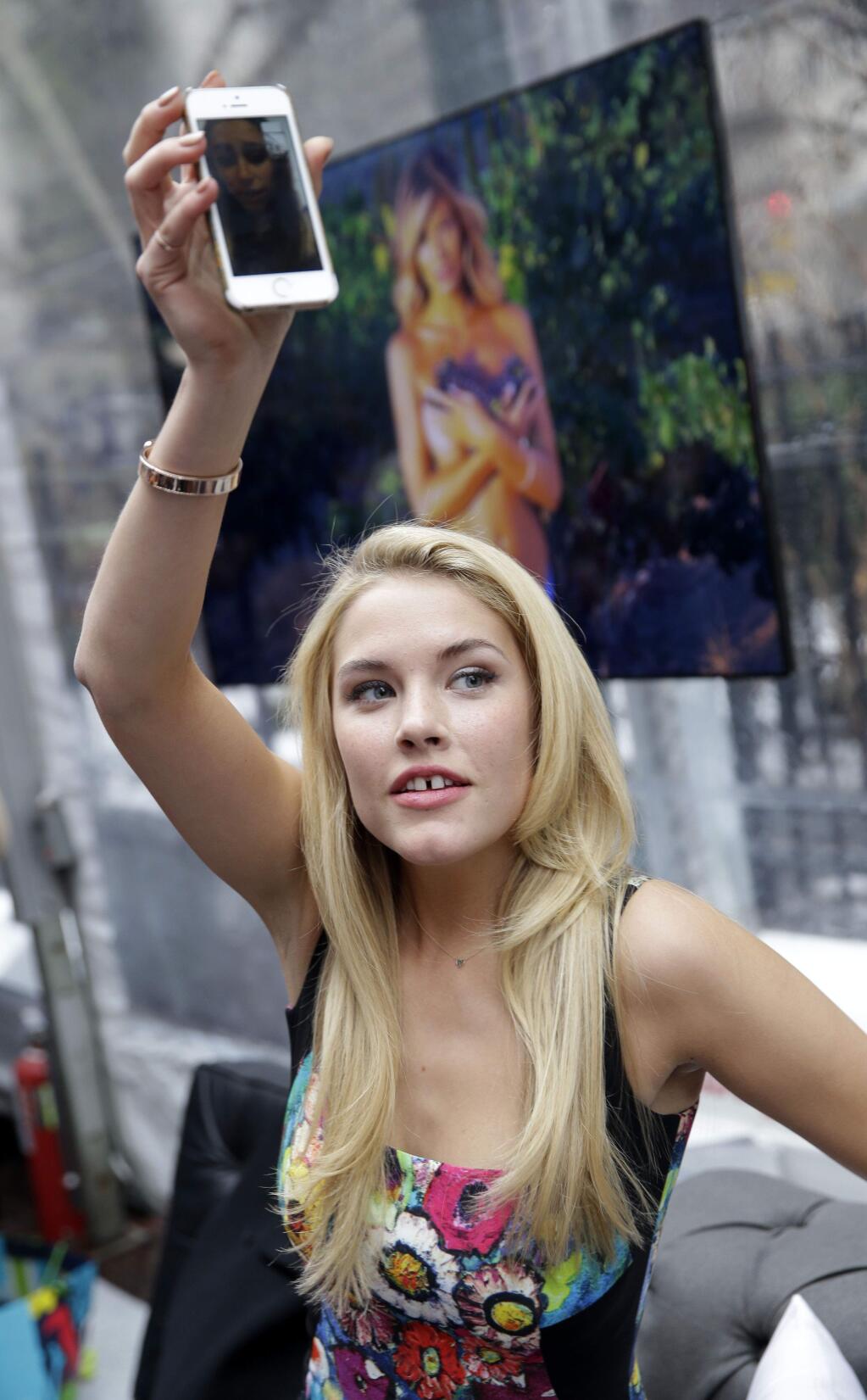 Sports Illustrated swimsuit model Ashley Smith gives a friend a view of the room via her phone at an event in New York, Monday, Feb. 9, 2015. Sports Illustrated is celebrating the release of the swimsuit issue with a festival where the public can meet the models and watch live music. (AP Photo/Seth Wenig)