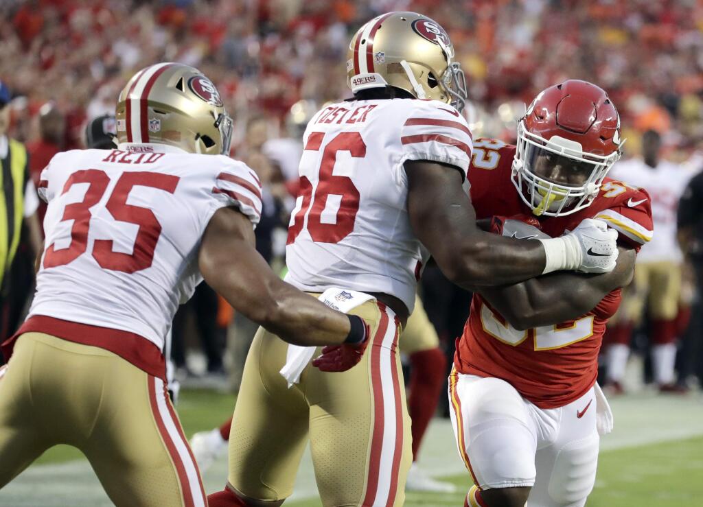 Kansas City Chiefs running back Spencer Ware (32) tries to get past San Francisco 49ers linebacker Reuben Foster (56) and safety Eric Reid (35) during the first half of a game in Kansas City, Mo., Friday, Aug. 11, 2017. (AP Photo/Charlie Riedel)