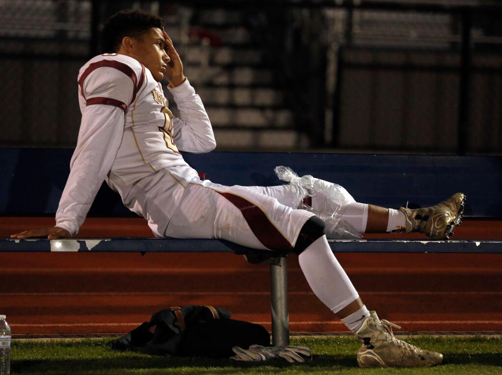 Cardinal Newman's Damian Wallace (8) sits on the bench after sustaining a knee injury during the first half of the NCS Division 4 championship football game on Saturday, Dec. 5, 2015. (Alvin Jornada / The Press Democrat)