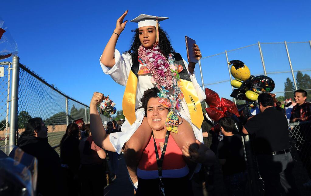 Piner High School graduate Gianna Louis-Jacques, 15, is hoisted by a relative as she celebrates her graduation two years early, Friday, June 1, 2018 in Santa Rosa. Louis-Jacques is also a full time student at Santa Rosa Junior College. (Kent Porter / The Press Democrat) 2018