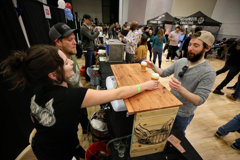 (From left) Shady Oak Barrel House employee Sarah Greer and owner Steve Doty serve beer to Jacob Horvat during the 6th annual NorCal Beer Geeks Festival at the Veterans Memorial Building in Santa Rosa on Sunday, January 12, 2020. (BETH SCHLANKER/ The Press Democrat)