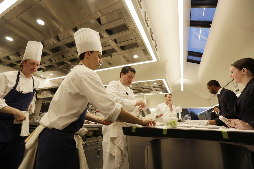 In this photo taken Thursday, March 9, 2017, servers wait for dishes being brought to the pass inside the new kitchen at the French Laundry restaurant in Yountville, Calif. Celebrated chef Thomas Keller has just opened a state-of-the art new kitchen at his famed French Laundry after spending $10 million on an extensive renovation. Unlike the stainless steel austerity of most commercial kitchens, this one is white, spacious and sunlit by skylights and two walls of wraparound windows overlooking the garden. (AP Photo/Eric Risberg)