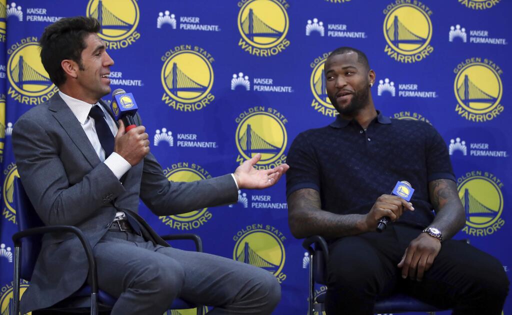 Golden State Warriors general manager Bob Myers, left, gestures beside DeMarcus Cousins during a media conference Thursday, July 19, 2018, in Oakland. Cousins signed a one-year, $5.3M deal with the defending champion Warriors. (AP Photo/Ben Margot)