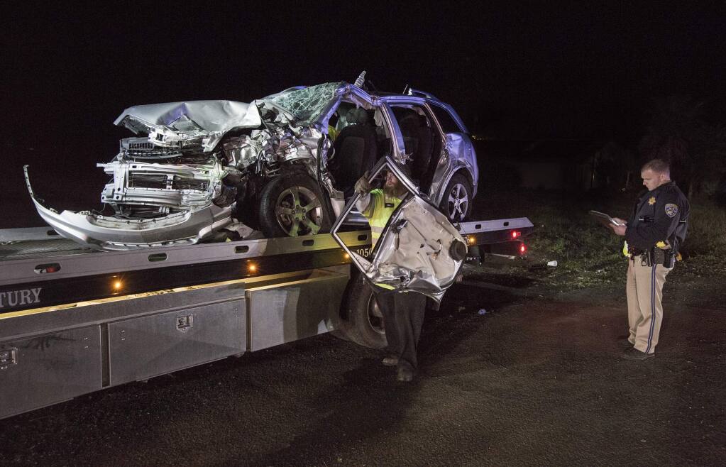 As the mangled Chevrolet is loaded onto a flatbed, a CHP officer takes details from one of the two cars involved in the head-on collision on Broadway at approximately 6:30 p.m., on Sunday, 13 January. (Photo by Robbi Pengelly/Index-Tribune)