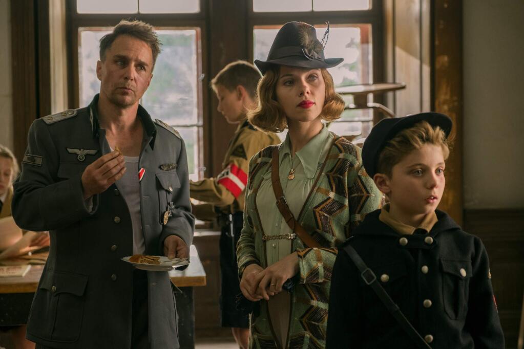 This image released by Fox Searchlight Pictures shows, from left, Sam Rockwell, Scarlett Johansson and Roman Griffin Davis in a scene from the WWII satirical film 'Jojo Rabbit.' (Larry Horricks/Fox Searchlight Pictures via AP)