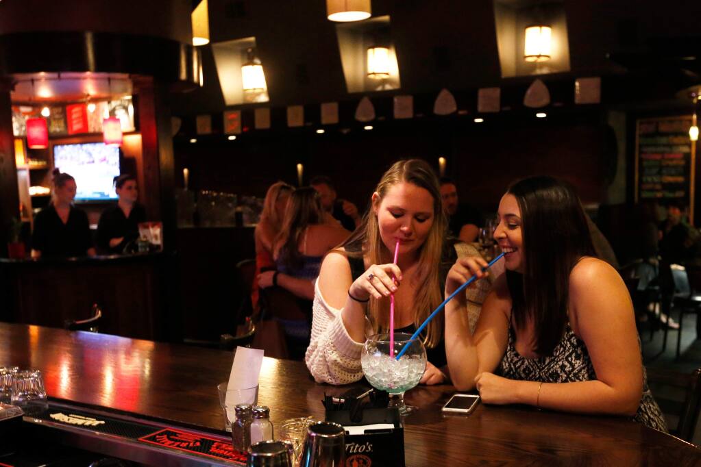 Sonoma State University students Kelsey Miller, left, and Gabriella Catalli share one of the signature Bowlas drinks at Tex Wasabi's in Santa Rosa, California on Wednesday, April 6, 2016. (Alvin Jornada / The Press Democrat)