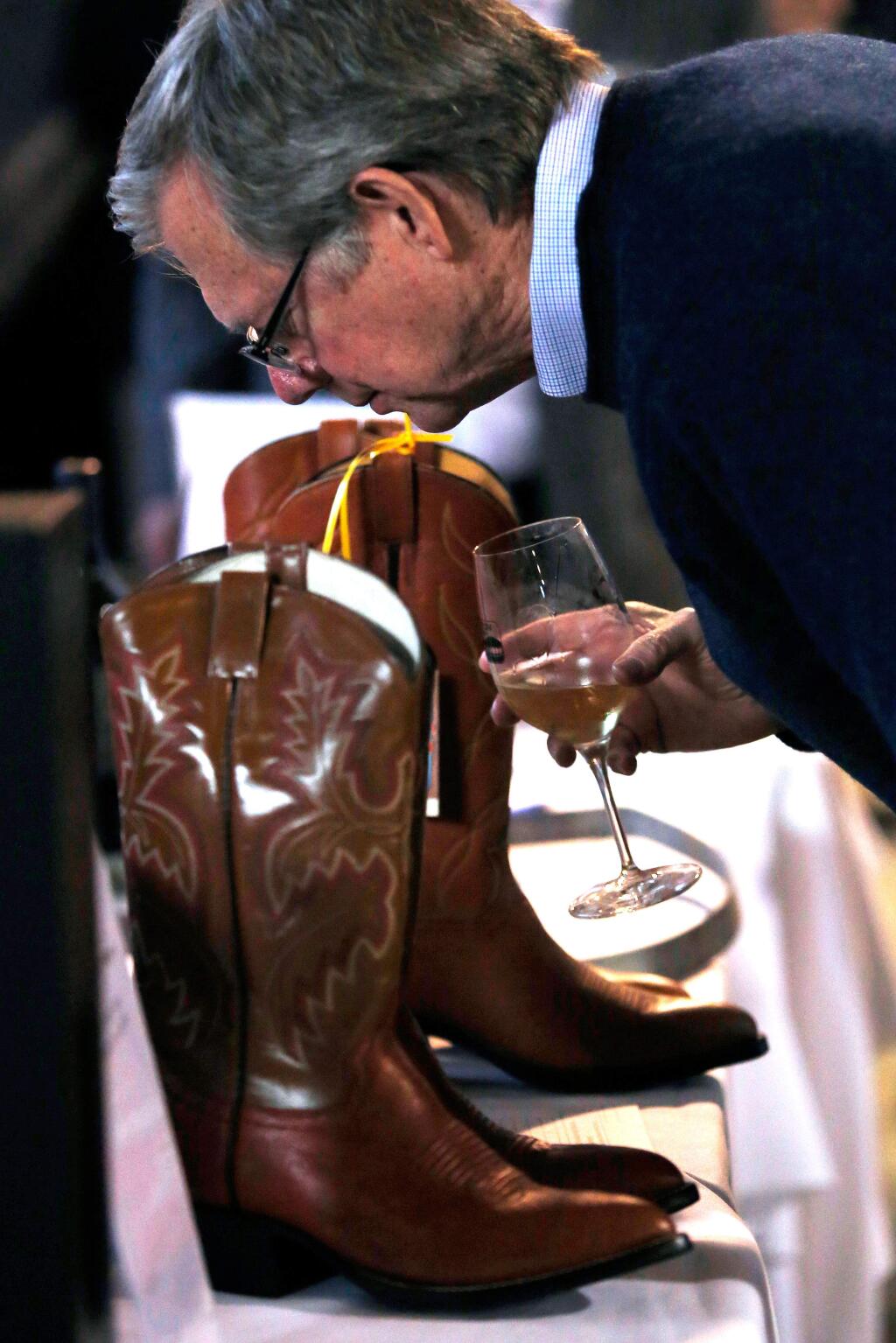 Tom Croft examines a pair of cowboy boots that he bid on in the silent auction during the SRJC AgTrust AgStravaganza, honoring vintners John and Terri Balletto, at Shone Farm in Forestville, California on Saturday, November 5, 2016. (Alvin Jornada / The Press Democrat)
