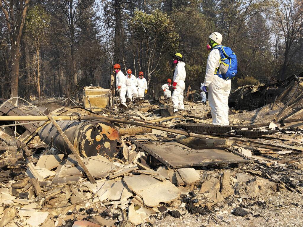 File - In this Nov. 18, 2018 file photo, volunteer members of an El Dorado County search and rescue team search the ruins of a home, looking for human remains, in Paradise, Calif., following a wildfire. Authorities have deployed a powerful tool to aid in their race to identify the remains of 77 bodies burned in the deadly wildfire that ripped through Northern California: Rapid DNA testing that produces results in just two hours. But the technology that can match DNA to bone fragments in as little as two hours is only as effective as the numbers of people who show up to give a sample, and so far there are not nearly enough volunteers. (AP Photo/Sudhin Thanawala, File)