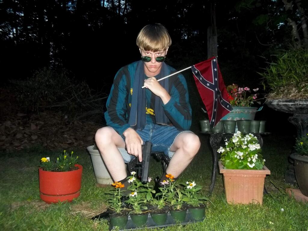 An image that appeared on Lastrhodesian.com shows Charleston, S.C., shooting suspect Dylann Roof posing while holding a Confederate battle flag and a handgun. (Lastrhodesian.com via AP)