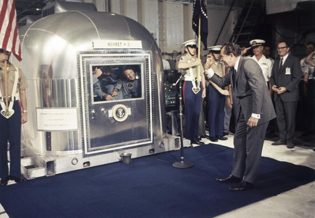 President Richard Nixon greets Apollo 11 astronauts Neil Armstrong, Michael Collins and Buzz Aldrin in a quarantine van aboard the USS Hornet on July 24, 1969. (Associated Press)