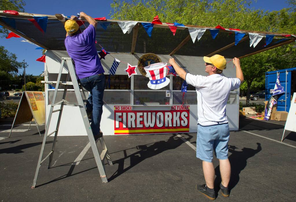 Don Canardo, left, and Mike Stanford hang Fourth of July banners on the Sebastopol Lions Club fireworks boot in the Safeway shopping center on the first day of legal fireworks sales in the county. (photo by John Burgess/The Press Democrat)