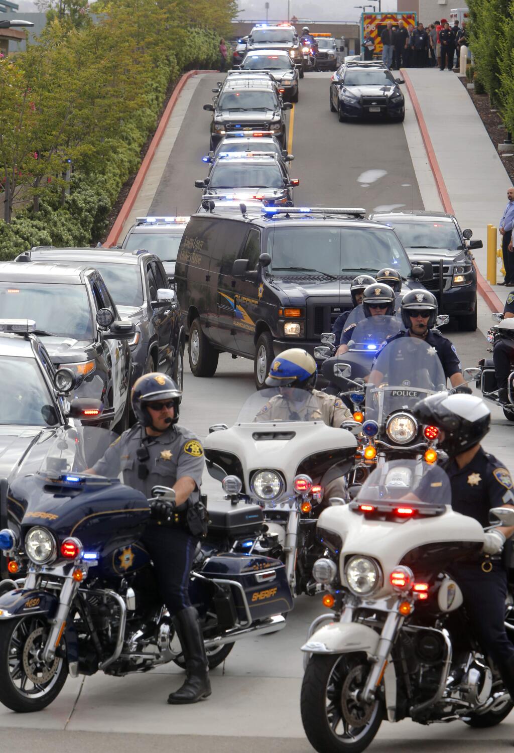 Police officers escort the Alameda County Coroner's van from the Eden Medical center after a Hayward police officer was shot and killed during a traffic stop in Hayward, Calif., on Wednesday, July 22, 2015. Sgt. Scott Lunger, 48, was shot in the early morning after he stopped a white Chevrolet pickup that was swerving on the road and driving erratically. (Michael Macor/San Francisco Chronicle via AP)