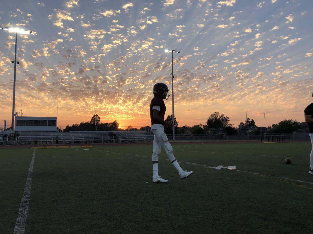 Junior quarterback Yonaton Isack walks across the Piner High School football field at a practice last week under the glow of new lights that will allow the Prospectors to play night games for the first time. (KERRY BENEFIELD/ PD)