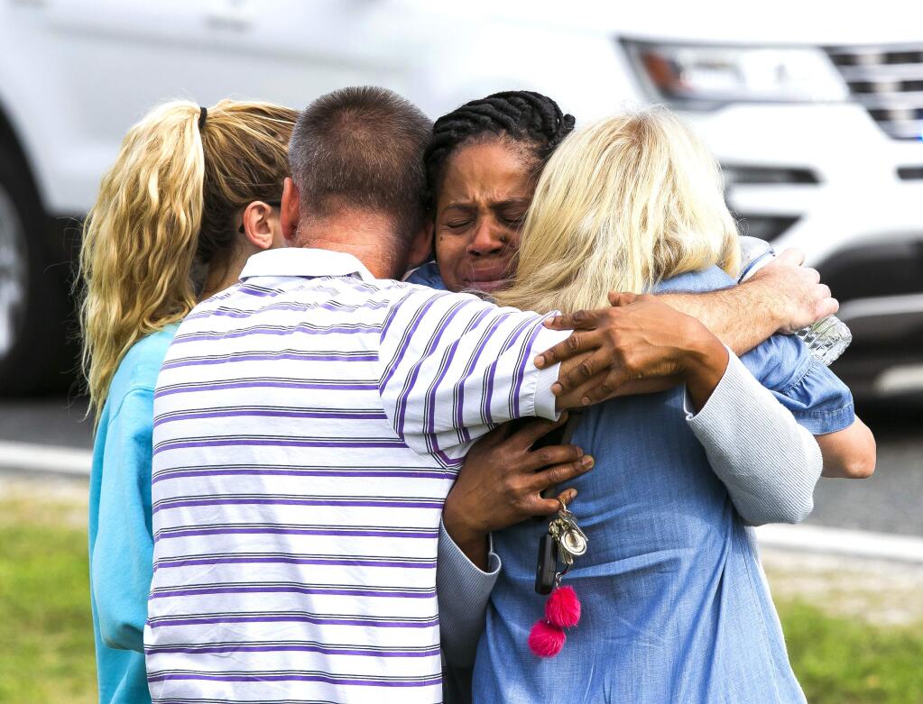 Nikki Brown, center, hugs others in front of Forest High School Friday, April 20, 2018 in Ocala, Fla. One student shot another in the ankle at the high school and a suspect is in custody, authorities said Friday. The injured student was taken to a local hospital for treatment. (Doug Engle /Star-Banner via AP)