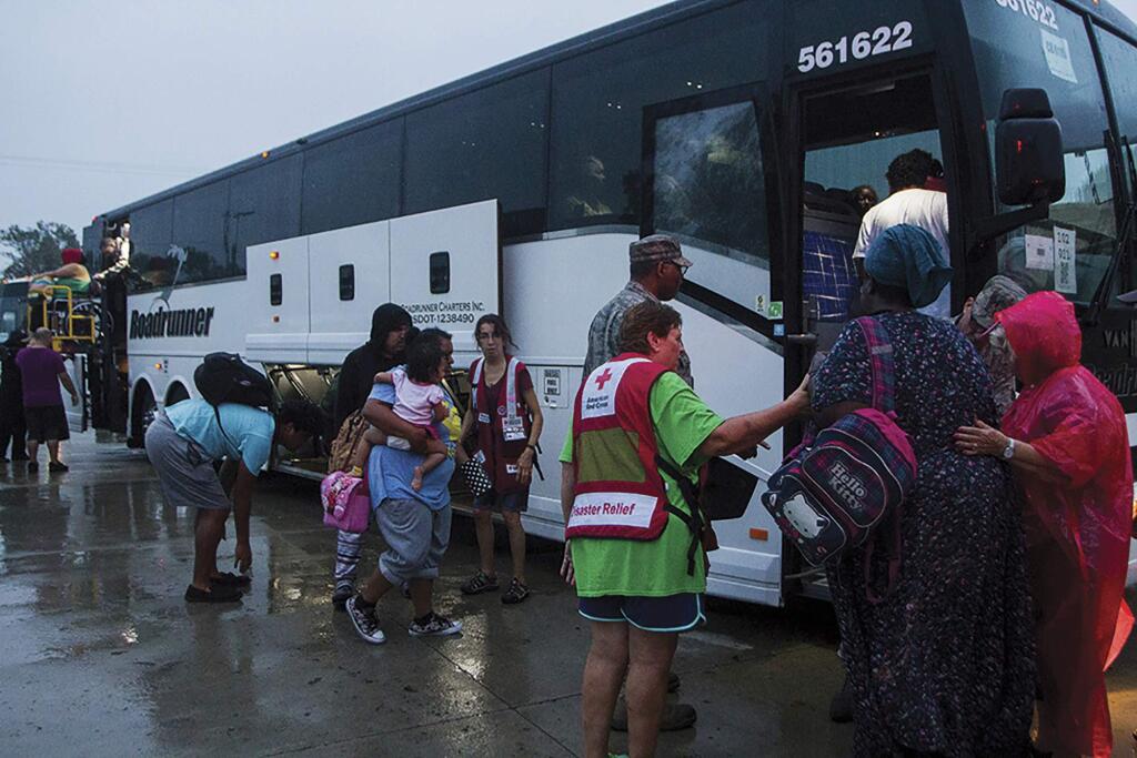In this Aug. 27, 2017 photo, Victoria residents are loaded onto buses to be transported from the emergency shelter dome at St. Joseph High School in Victoria, Texas to Austin. The residents are being moved due to rising waters and the city's water being shut off. (Nicolas Galindo/The Victoria Advocate via AP)
