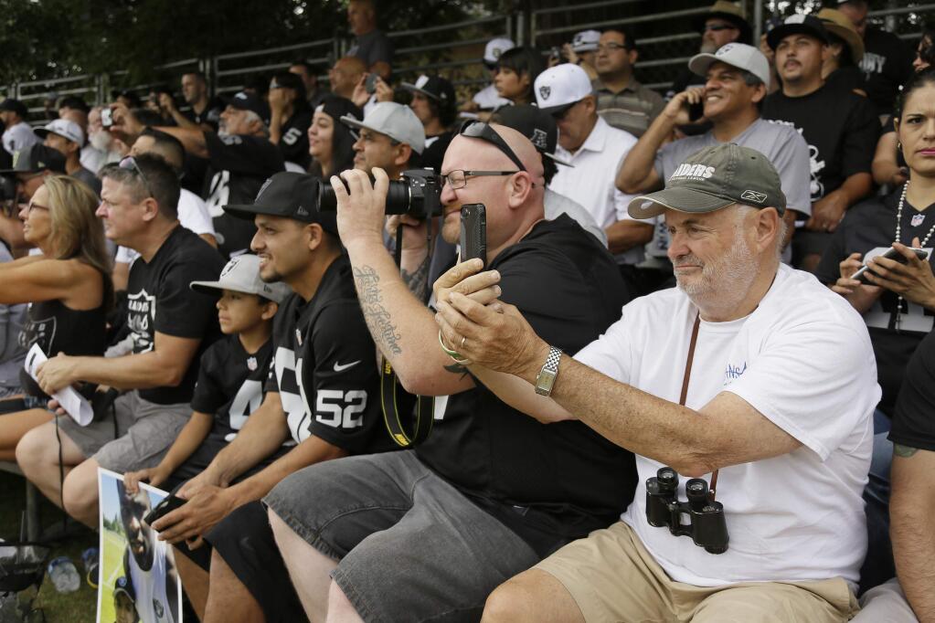 Spectators follow Oakland Raiders running back Marshawn Lynch as he stretches in front of them during an NFL football training camp Friday, Aug. 4, 2017, in Napa, Calif. (AP Photo/Eric Risberg)