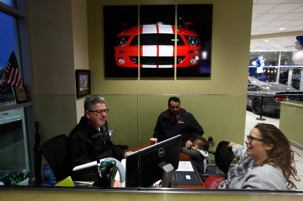 Nicole Holmes, right, of Santa Rosa, along with her daughter Kismet Samainego, 1, and father Kismet Holmes, sits down with Hansel Ford customer retention manager David Pappas, left, to discuss purchasing a preowned vehicle at Hansel Ford in Santa Rosa, California, on Thursday, February 22, 2018. (Alvin Jornada / The Press Democrat)