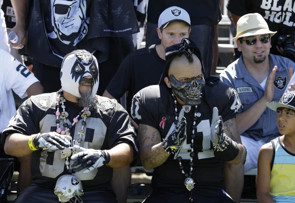 Oakland Raiders fans cheer on the sidelines during the NFL football team's training camp Saturday, July 26, 2014, in Napa. (AP Photo/Eric Risberg)