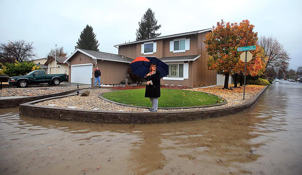 Regina Legoski checks out the flooded neighborhood from her neighbor's front yard on Flores Avenue in Rohnert Park on Thursday, Dec. 15, 2016. (KENT PORTER/ PD)