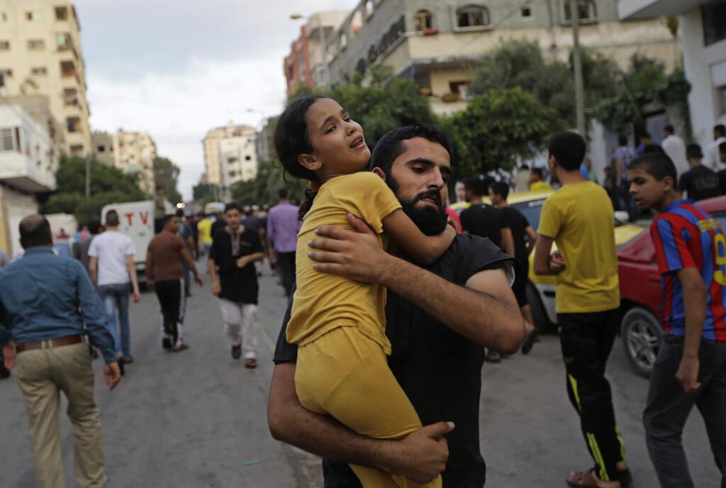 A Palestinian man carries away a girl, that was overcome by emotion, during the funeral of Muhammed Abu Shagfa, 7, killed in an explosion, in Shati refugee camp, in the northern Gaza Strip, Monday, July 28, 2014. An explosion killed 10 people, 9 of them children, at a park at Shati refugee camp, in northern Gaza Strip. Israeli and Palestinian authorities traded blame over the attack and fighting in the war raged on despite a major Muslim holiday. (AP Photo/Lefteris Pitarakis)