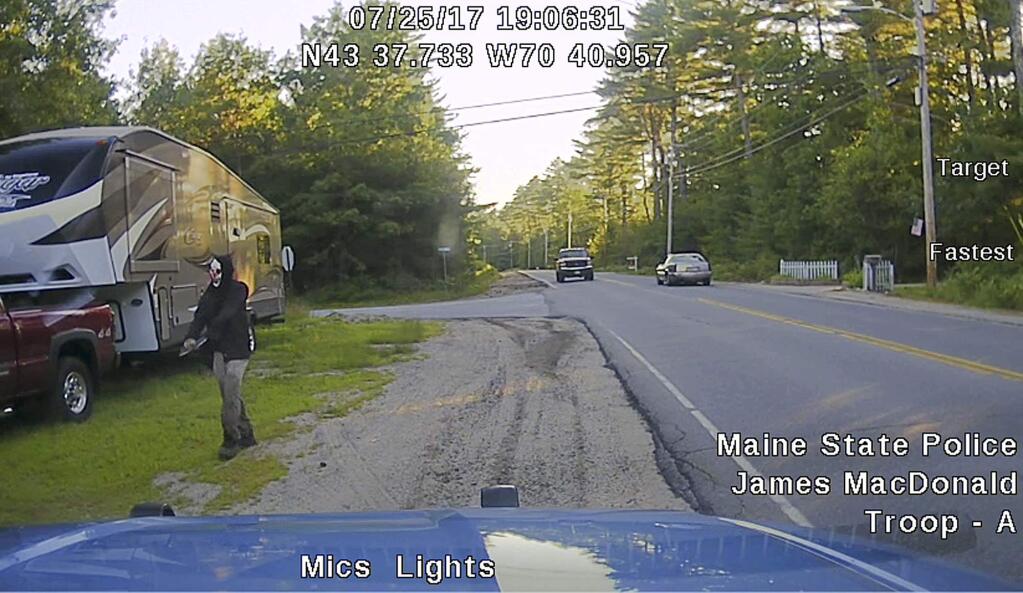 This Tuesday, July 25, 2017 patrol car dashboard camera image released by the Maine State Police shows a man strolling down a street in Hollis, Maine, who police said was wearing a clown mask with a machete taped to his amputated arm. Police said the man, Corey Berry, 31, of Hollis, was arrested and charged with criminal threatening. He was released after posting bail. (Maine State Police via AP)