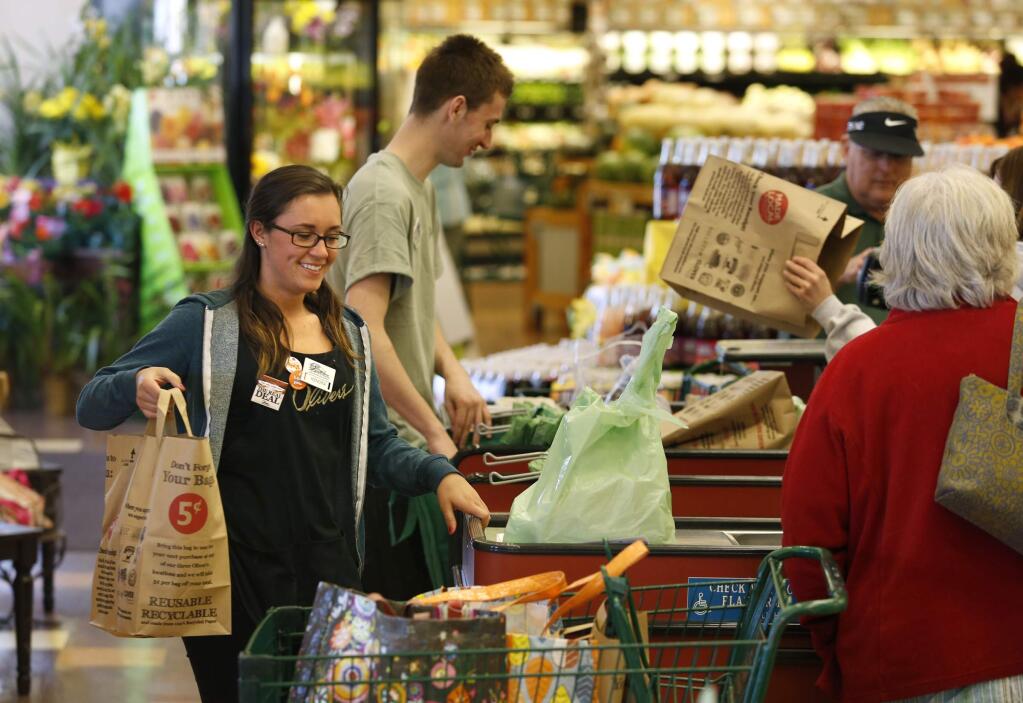 Employee Shelby Atwood loads a bag of groceries into Barbara Iannoli's cart at Oliver's Market on Wednesday, March 19, 2014 in Santa Rosa, California. (BETH SCHLANKER/ The Press Democrat)