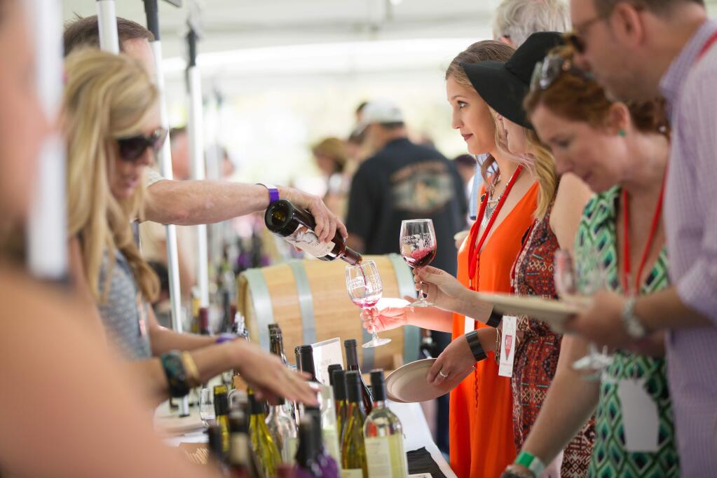 Emily Kelso, center right, receives a wine pour at The Press Democrat North Coast Wine Tasting event held at the Sonoma Mountain Village Event Center In Rohnert Park Sunday afternoon, May 15, 2016. This event featured the highest scoring wines from the 2016 North Coast Wine Challenge paired with food prepared by local chefs. Over 75 wines were featured at the event.( Photo by Charlie Gesell for the Press Democrat)