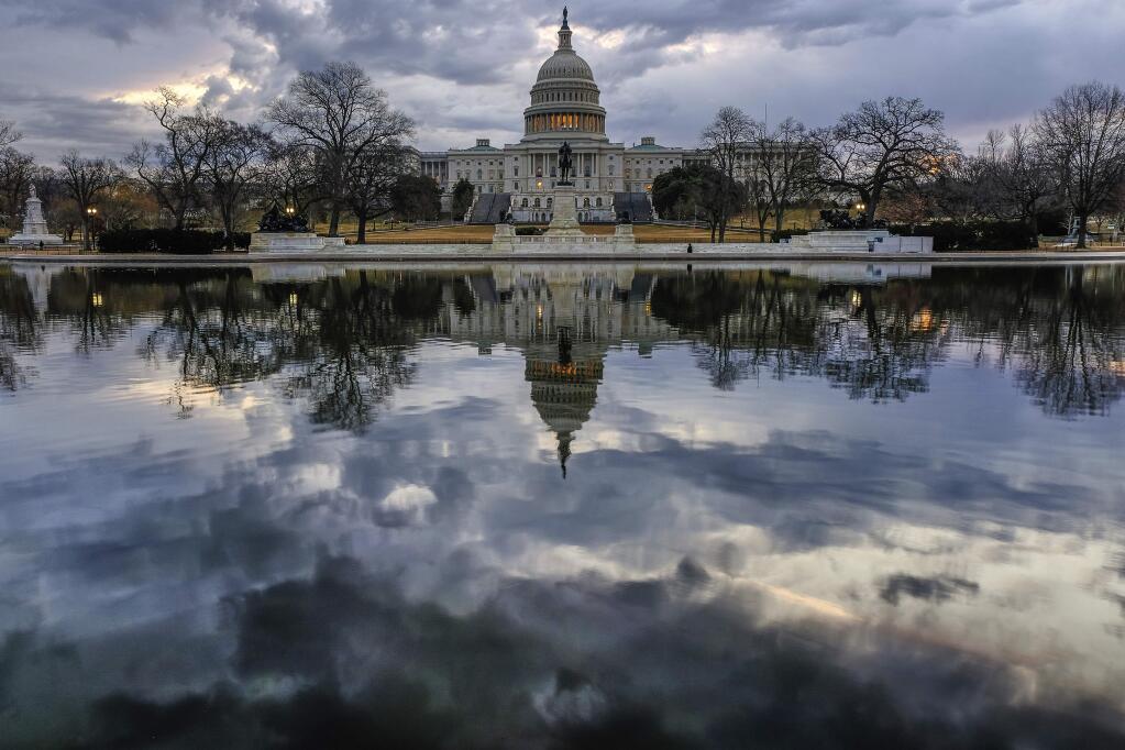 Clouds are reflected in the U.S. Capitol reflecting pool at daybreak in Washington as Day Three of the government shutdown continues, Monday, Jan. 22, 2018. (AP Photo/J. David Ake)