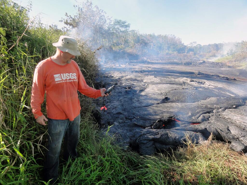 In this Oct. 22, 2014 photo provided by the U.S. Geological Survey, a geologist marks the coordinates of the Kilauea lava flow front with a GPS unit. A 13-mile finger of lava from Kilauea Volcano has started to again move quickly, and could hit a secondary road sometime Friday, Oct. 24, 2014. Officials on Hawaii's Big Island won't start evacuating people until the lava flow is within three to five days of affecting Pahoa residents. (AP Photo/U.S. Geological Survey)
