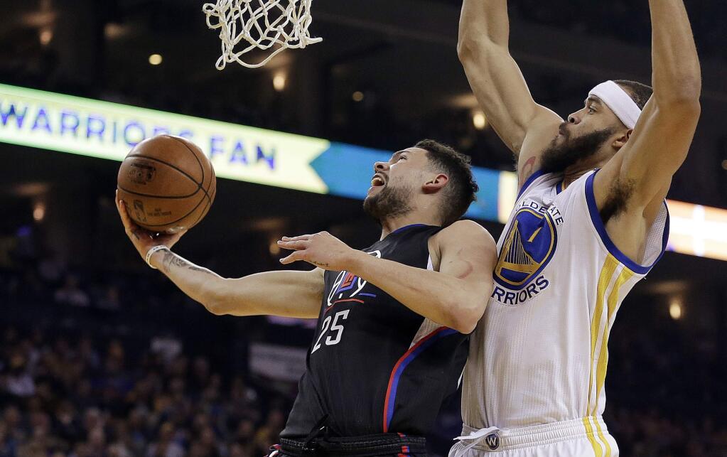 Los Angeles Clippers' Austin Rivers, left, lays up a shot past Golden State Warriors' JaVale McGee (1) during the first half of an NBA basketball game Thursday, Feb. 23, 2017, in Oakland, Calif. (AP Photo/Ben Margot)