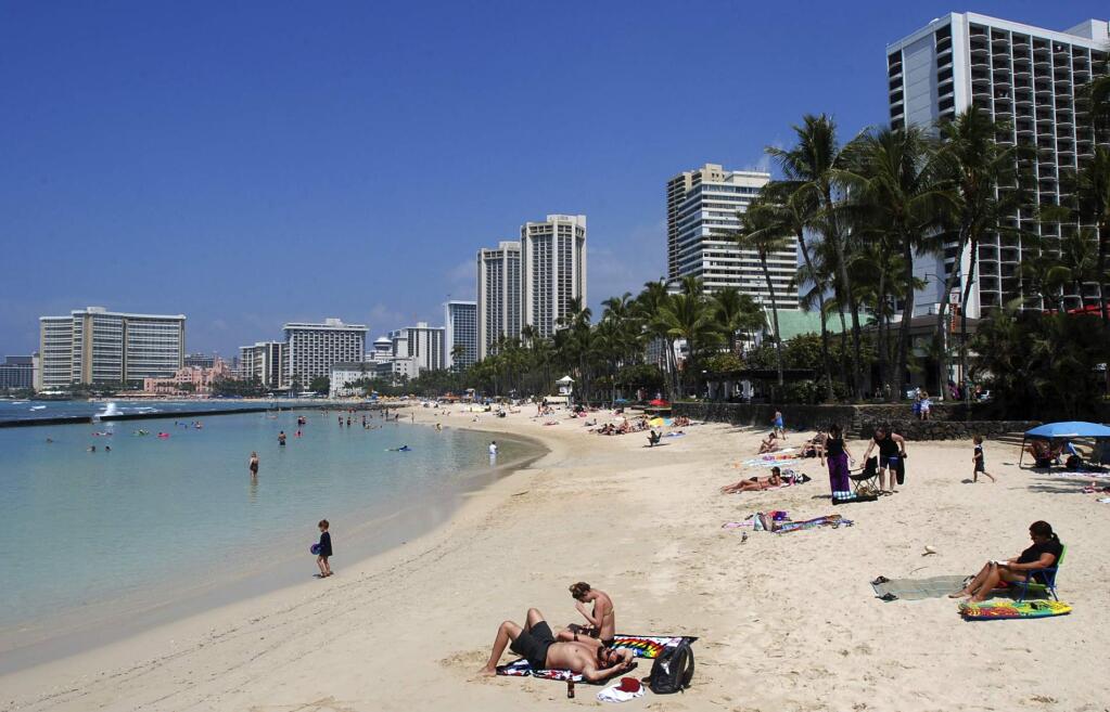 FILE - In this March 13, 2017, file photo, people relax on the beach in Waikiki in Honolulu. (AP Photo/Caleb Jones, File)