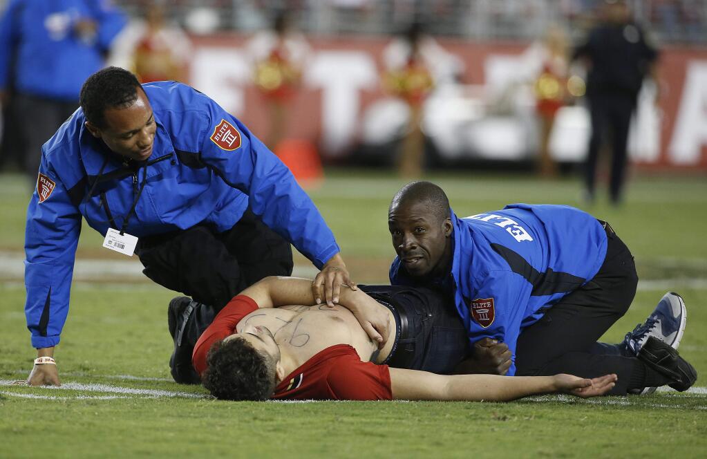 FILE - In this Sept. 12, 2016, file photo, a fan is tackled by security officers during the second half of an NFL football game between the San Francisco 49ers and the Los Angeles Rams in Santa Clara, Calif. Westwood One radio announcer Kevin Harlan's call of the fan's movements has become a trending topic online. (AP Photo/Tony Avelar, File)