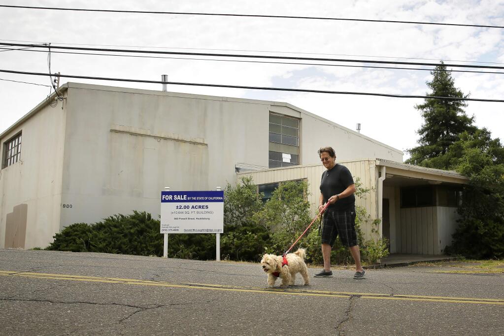 Dennis McGinness walks his dog Santi by the Healdsburg Armory along Powell Avenue in Healdsburg on Wednesday, July 16, 2014. The state-owned building is for sale as surplus property. (Conner Jay/The Press Democrat)