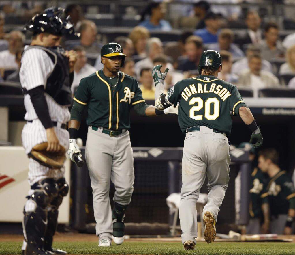 Oakland A's on deck-batter Yoenis Cespedes, center, greets Josh Donaldson (20) after Donaldson hit the go-ahead home run off Yankees reliever Jose Ramirez, Wednesday, June 4, 2014. New York Yankees catcher John Ryan Murphy (66) reacts at the plate. (AP Photo/Kathy Willens)