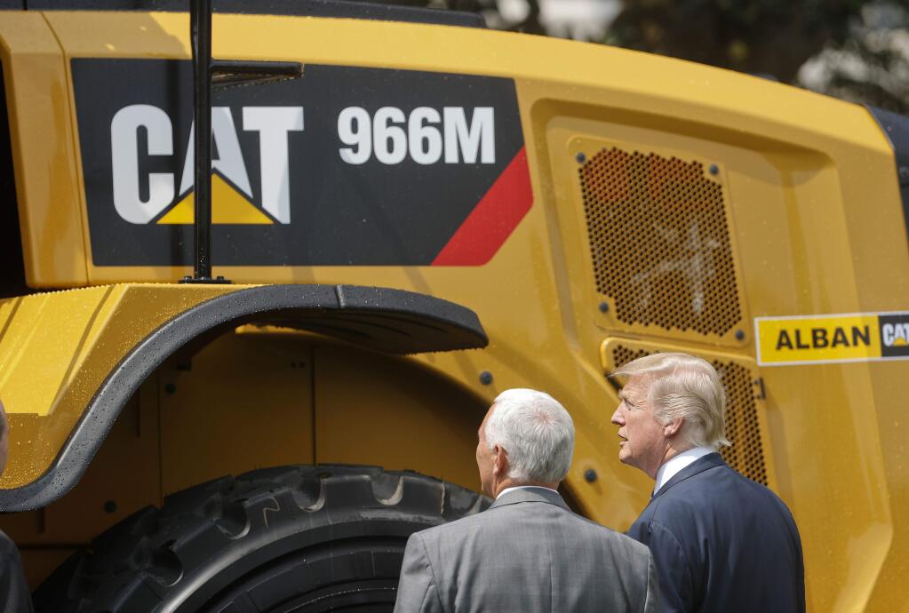 President Donald Trump and Vice President Mike Pence stop to looks at a Caterpillar truck, manufactured in Illinois, on the South Lawn of the White House in Washington, Monday, July 17, 2017, during a 'Made in America,' product showcase featuring items created in each of the U.S. 50 states. (AP Photo/Pablo Martinez Monsivais)